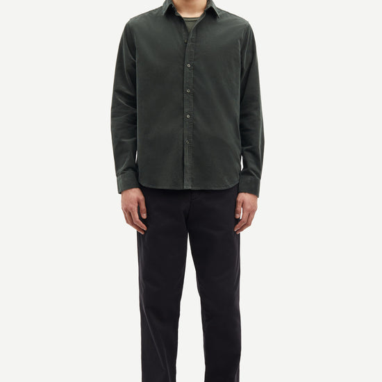 Man wearing a dark green button-up shirt and black pants on a white background from Samsoe Samsoe