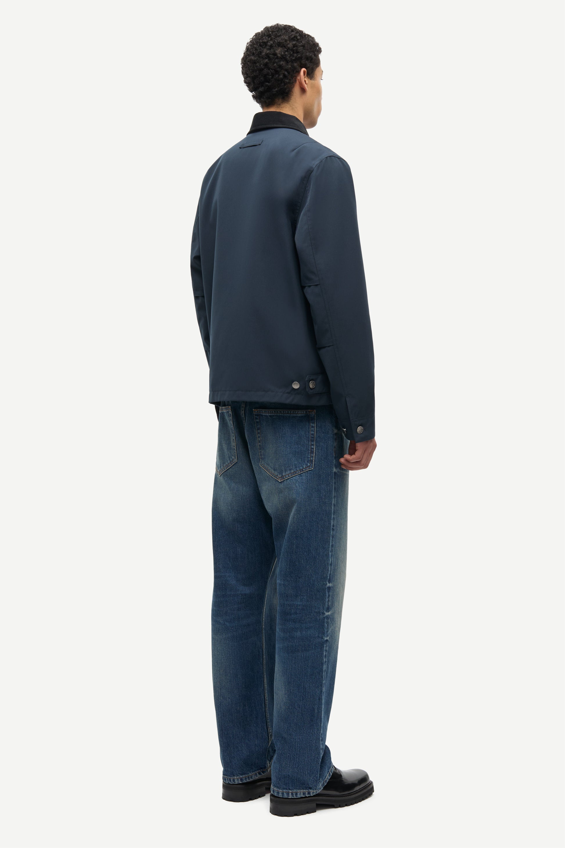 Man wearing a dark jacket and blue jeans on a white background from Samsoe Samsoe