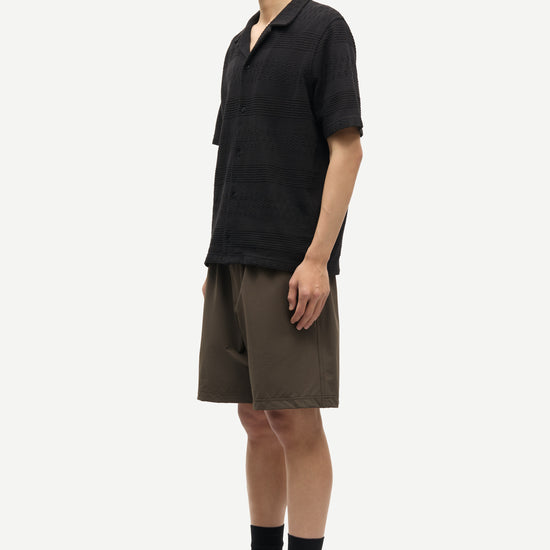 Man wearing a black shirt and brown shorts on a white background
