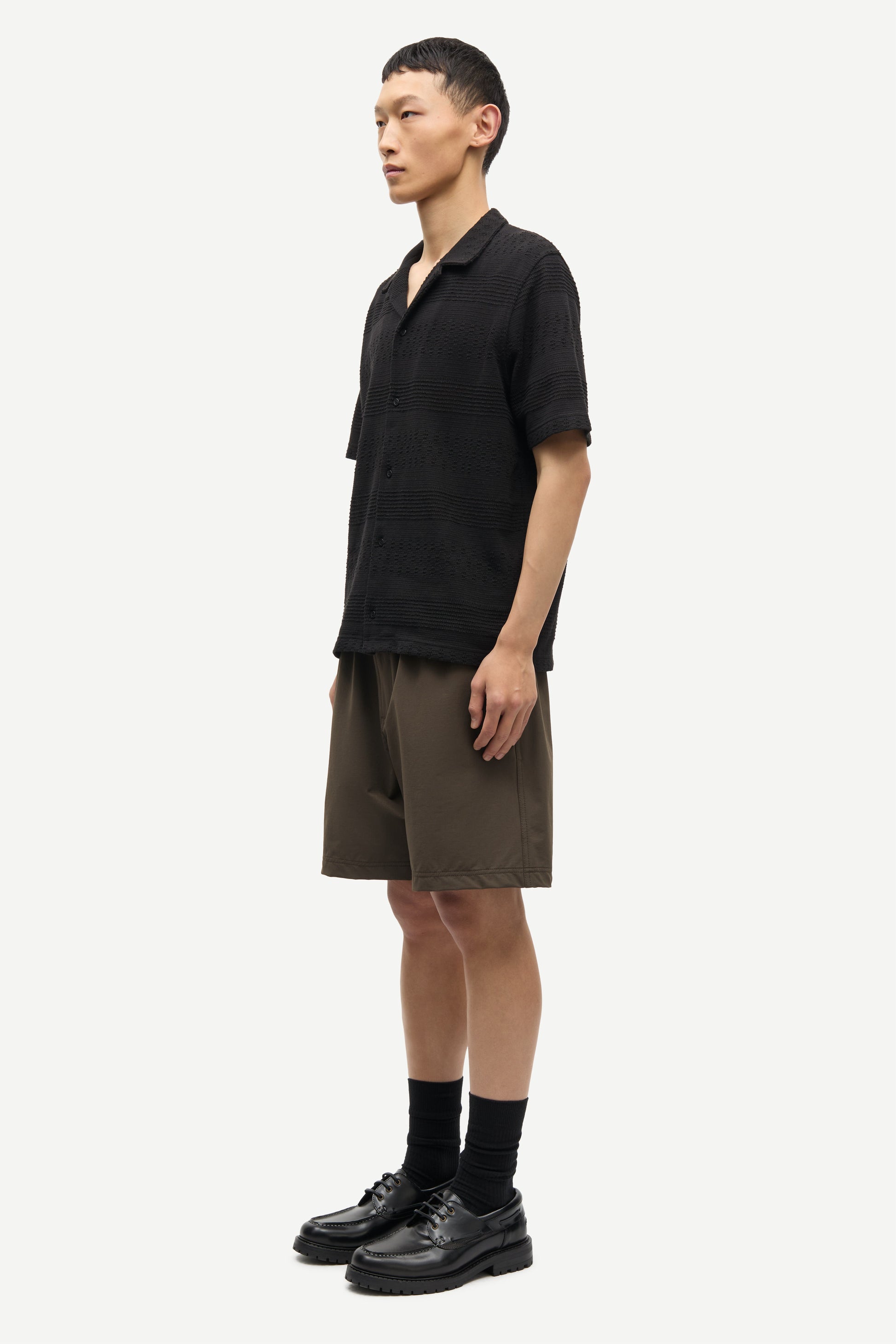 Man wearing a black shirt and brown shorts on a white background