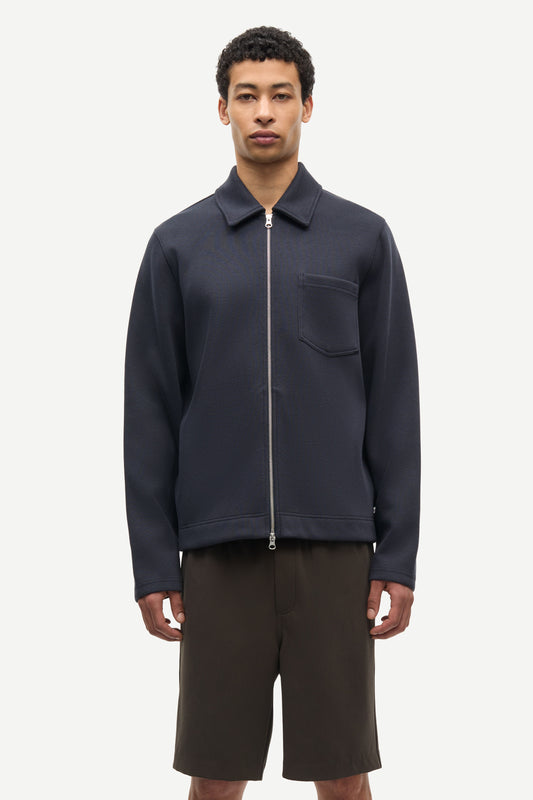 Man wearing a navy jacket with a zipper and a pocket on a white background