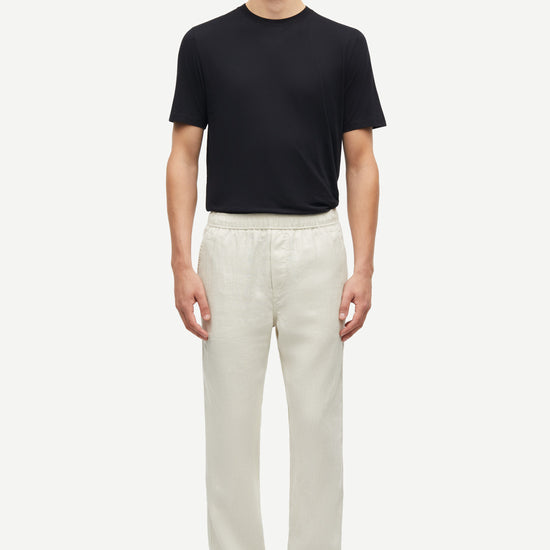 Man wearing a black t-shirt and white pants on a white background