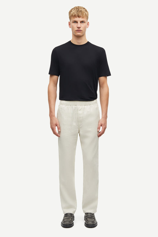 Man wearing a black t-shirt and white pants on a white background