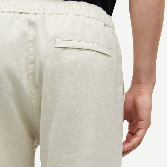 Close-up of a person wearing light-colored pants on a plain background