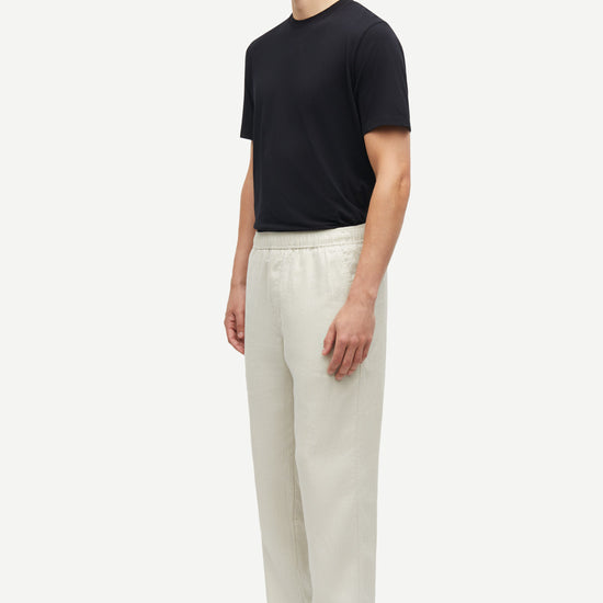 Man wearing a black t-shirt and white pants on a white background