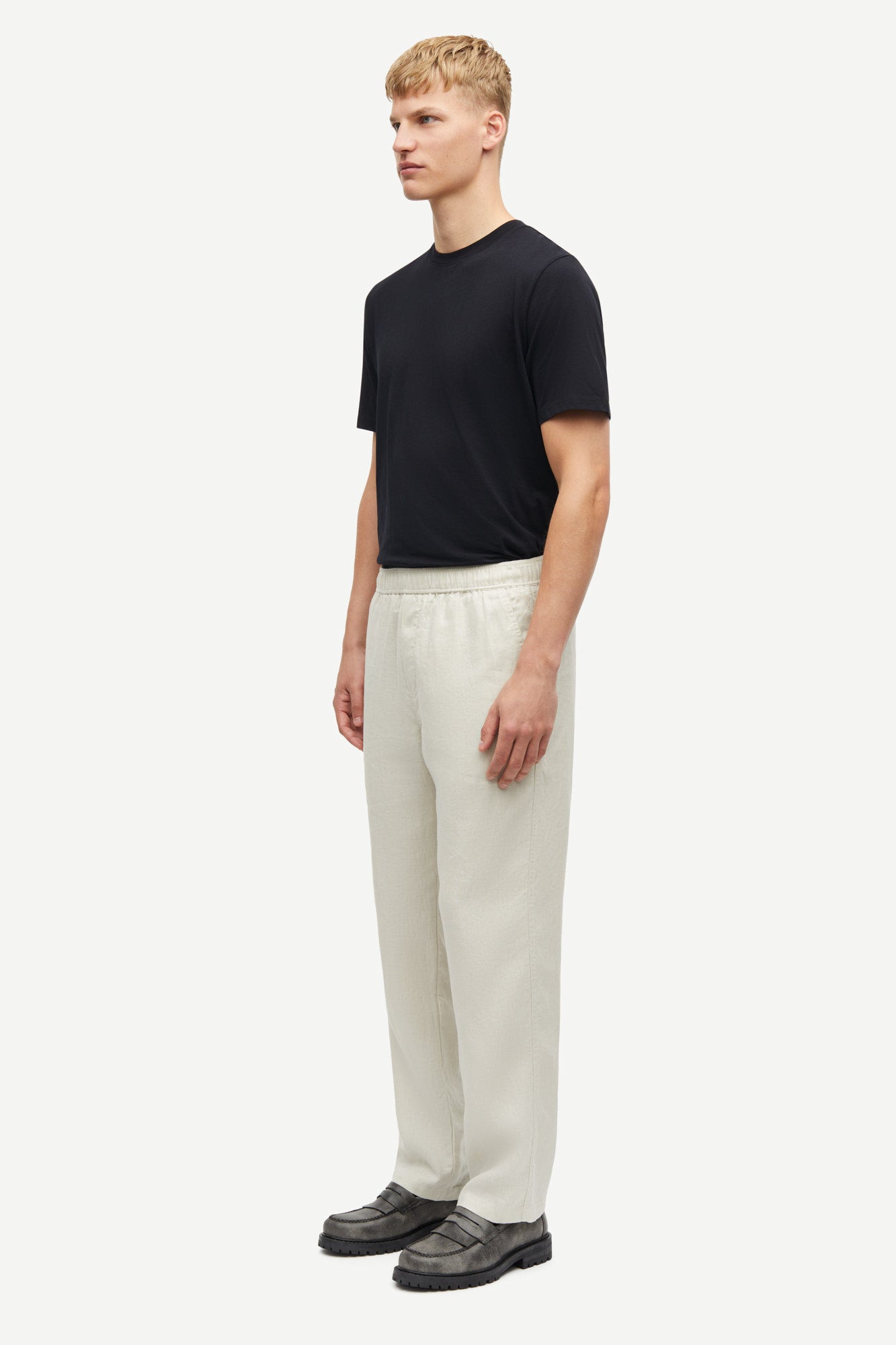 Man wearing a black t-shirt and white pants on a white background