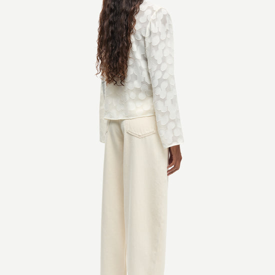 Rear view of cream long sleeve top worn with cream trousers