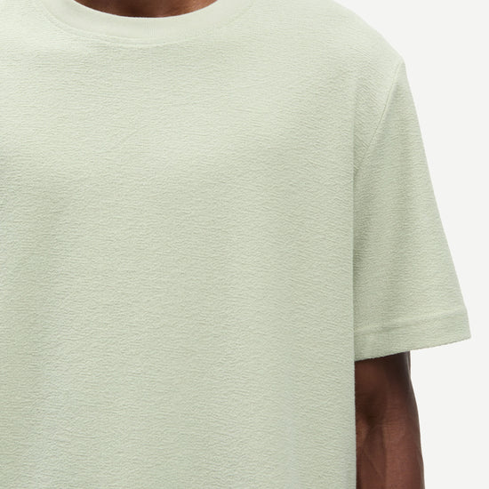 Light green t-shirt worn by a person on a white background