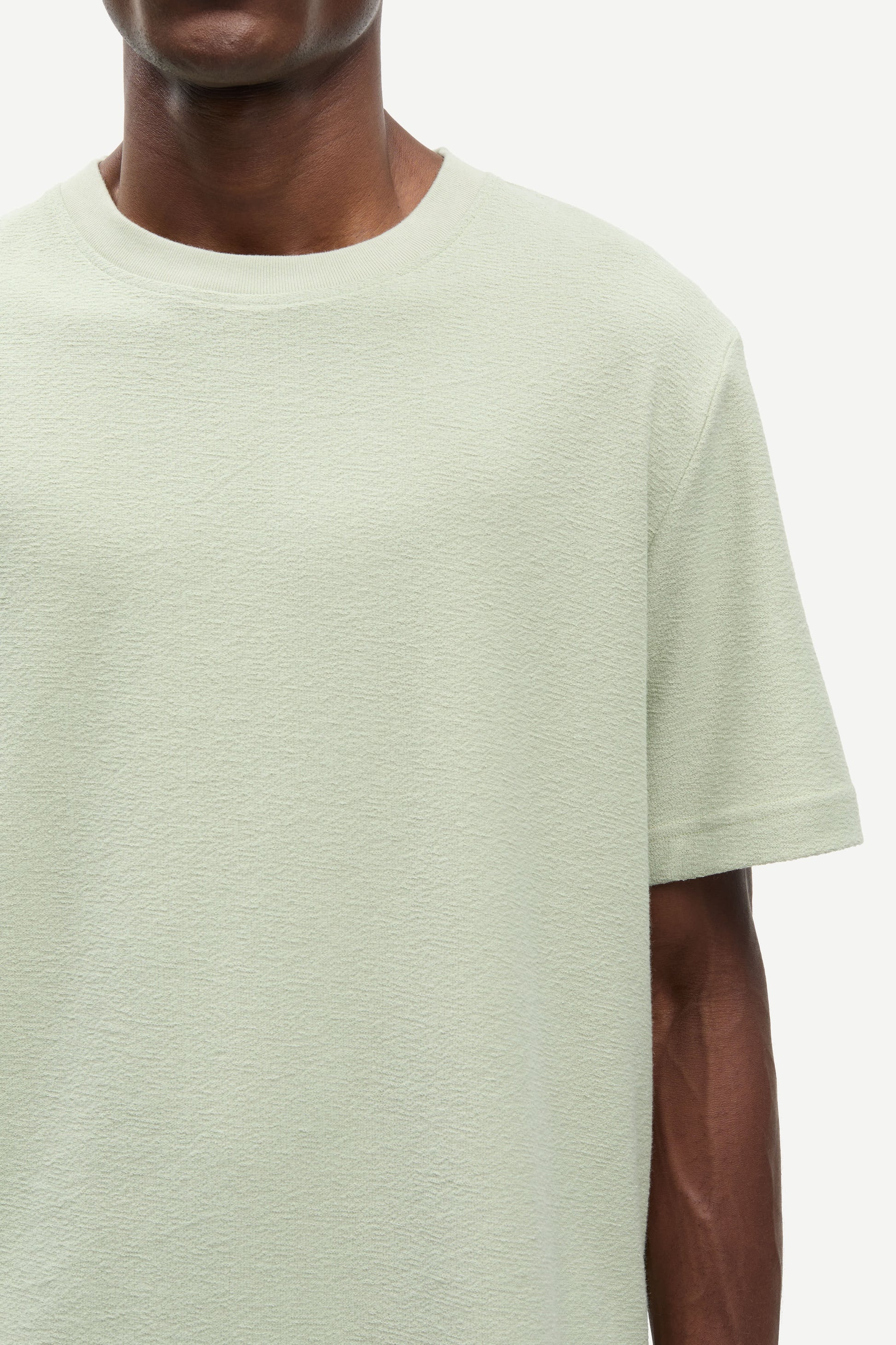 Light green t-shirt worn by a person on a white background
