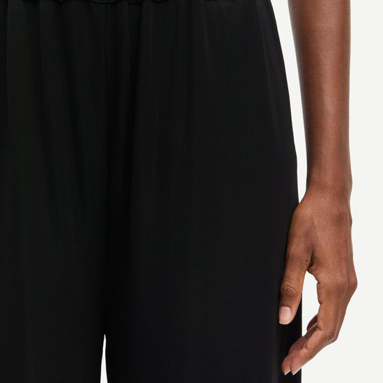 Black pants worn by a person on a white background