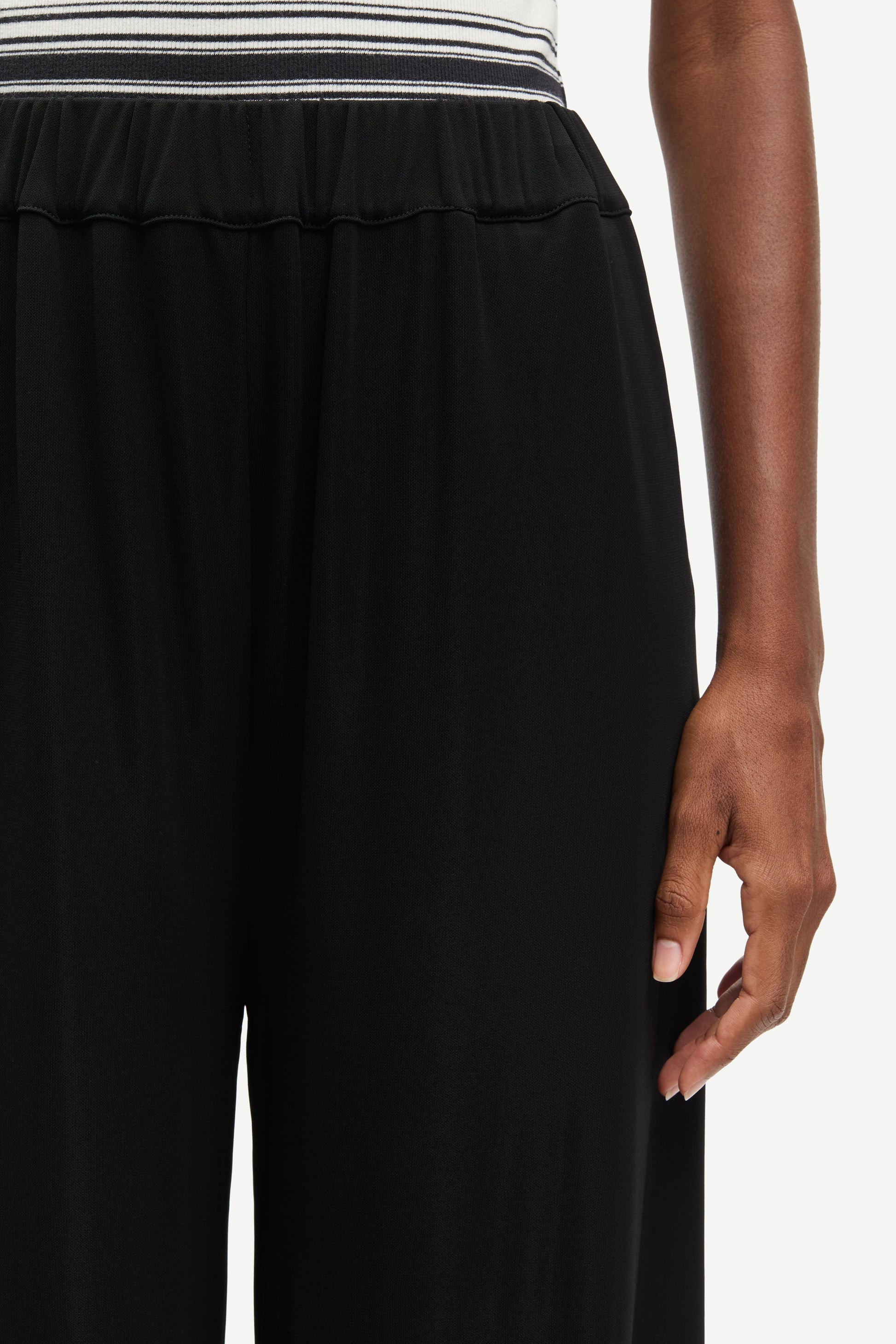 Black pants worn by a person on a white background
