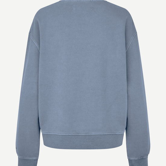 A dusty blue crewneck sweatshirt shown from the back, featuring a relaxed fit with ribbed cuffs and hem, displayed on a clean off-white background.