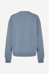 A dusty blue crewneck sweatshirt shown from the back, featuring a relaxed fit with ribbed cuffs and hem, displayed on a clean off-white background.
