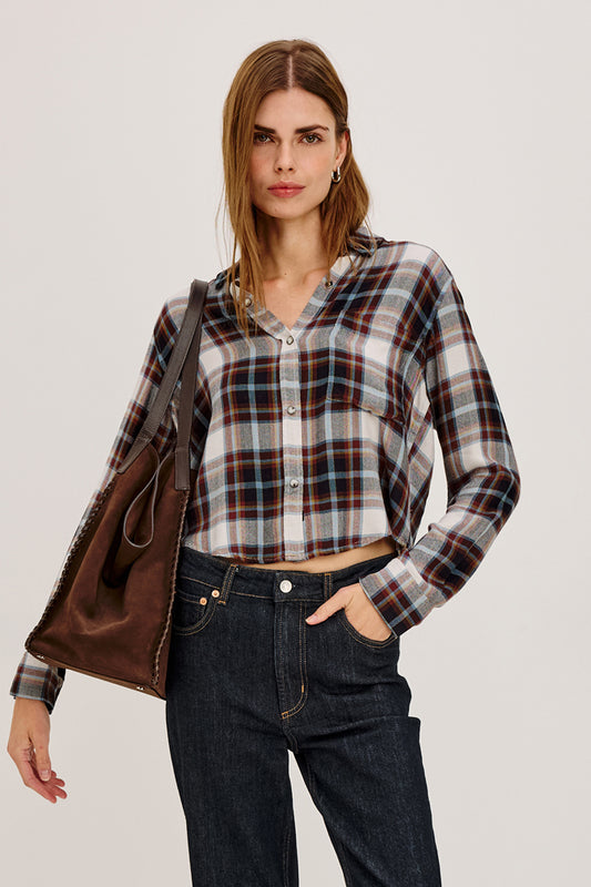 Woman wearing a plaid shirt with a brown leather jacket over her shoulder.