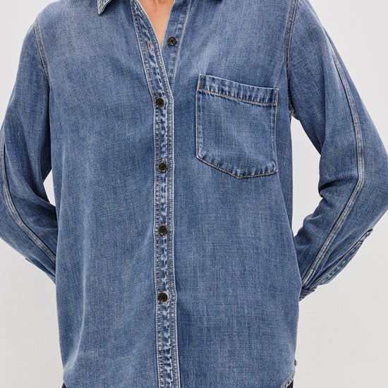 Denim shirt worn by a person on a plain background
