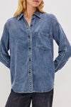 Denim shirt worn by a person on a plain background