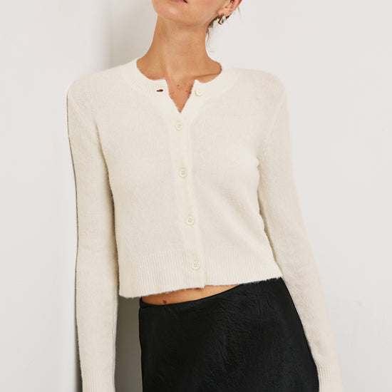 Cream cropped cardigan worn with a black skirt