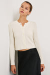 Cream cropped cardigan worn with a black skirt