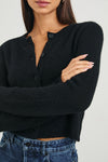 Person wearing a black cardigan and blue jeans against a white background