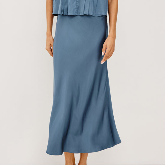 Woman wearing a blue sleeveless top and skirt on a white background