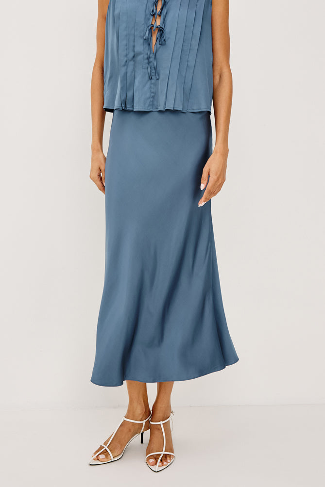 Woman wearing a blue sleeveless top and skirt on a white background