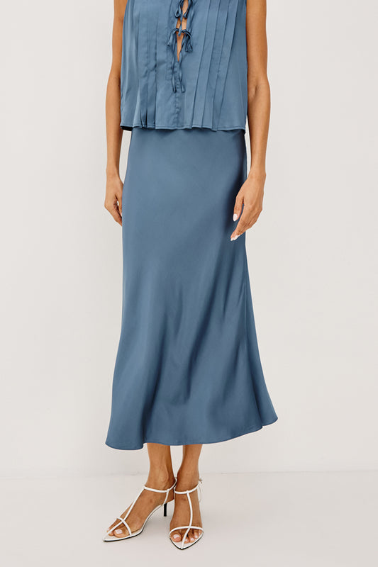 Woman wearing a blue sleeveless top and skirt on a white background