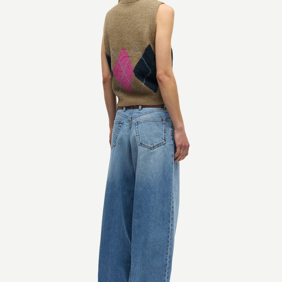 A model shown from the back wearing a brown sleeveless knit vest with a pink and black geometric pattern on the back, paired with wide-leg blue jeans, against a light gray background.