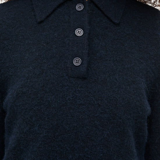 Close-up of a person wearing a dark navy knit polo sweater with a three-button placket.