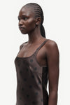 A model shown in profile wearing a dark brown camisole top with black polka dots, set against a plain light gray background.