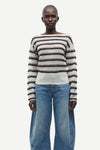 model wearing striped boat neck jumper and jeans on white background 