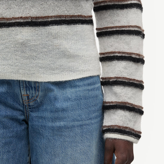 model wearing striped boat neck jumper and jeans on white background close up