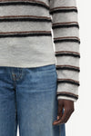 model wearing striped boat neck jumper and jeans on white background close up