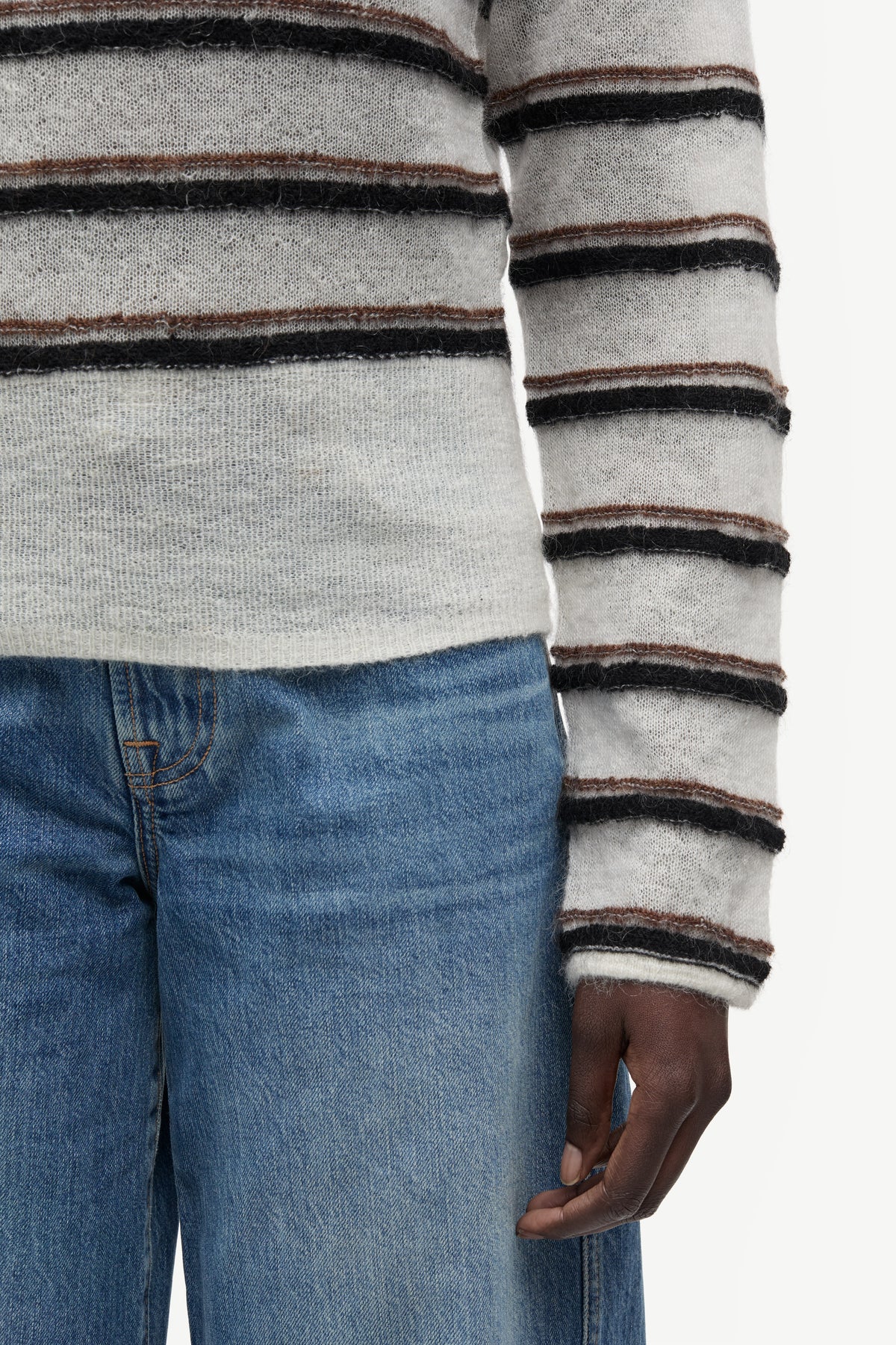 model wearing striped boat neck jumper and jeans on white background close up
