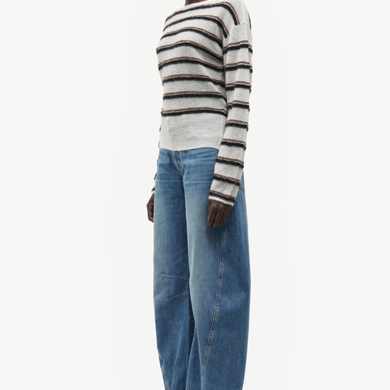 model wearing striped boat neck jumper and jeans on white background side view