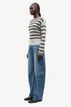 model wearing striped boat neck jumper and jeans on white background side view