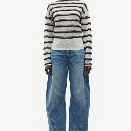 model wearing striped boat neck jumper and jeans on white background