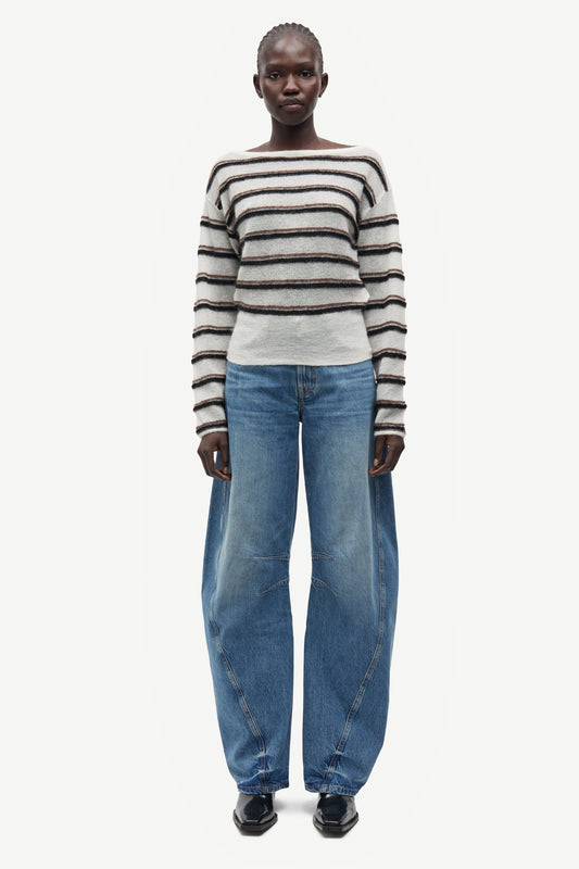 model wearing striped boat neck jumper and jeans on white background