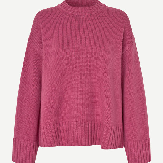 A pink ribbed knit crewneck sweater with dropped shoulders and ribbed cuffs, displayed on a clean off-white background.