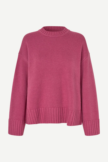 A pink ribbed knit crewneck sweater with dropped shoulders and ribbed cuffs, displayed on a clean off-white background.