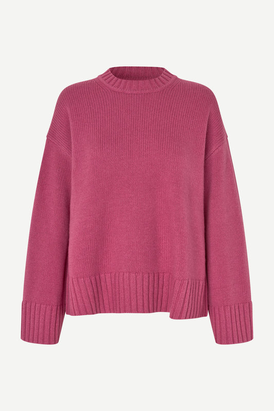 A pink ribbed knit crewneck sweater with dropped shoulders and ribbed cuffs, displayed on a clean off-white background.