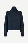 A dark navy blue knit turtleneck sweater with long balloon sleeves, shown on a plain light gray background.