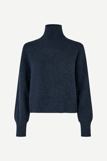 A dark navy blue knit turtleneck sweater with long balloon sleeves, shown on a plain light gray background.