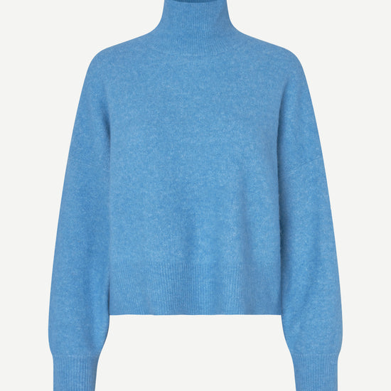 A light blue knit turtleneck sweater with long sleeves and ribbed cuffs, displayed on a clean, light off-white background.