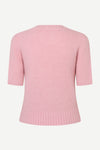 A light pink short-sleeve knit sweater shown from the back, featuring ribbed collar, cuffs, and hem, on a plain light gray background.