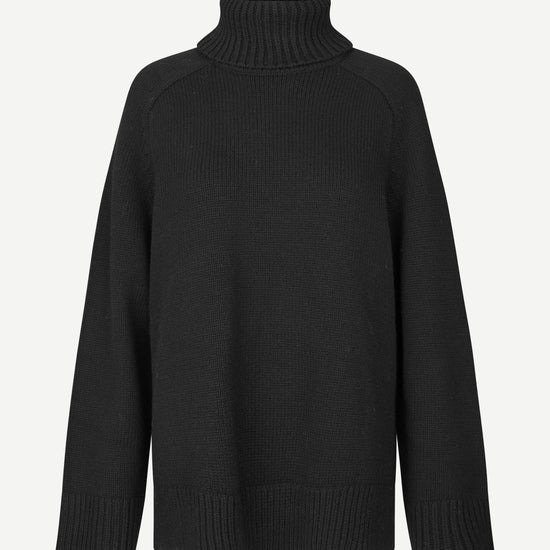 A black ribbed-knit turtleneck sweater with raglan sleeves, shown against a plain light gray background.