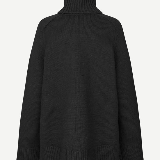 A black knit turtleneck sweater shown from the back, featuring a ribbed high collar, shoulders, cuffs, and hem, set against a plain light gray background.
