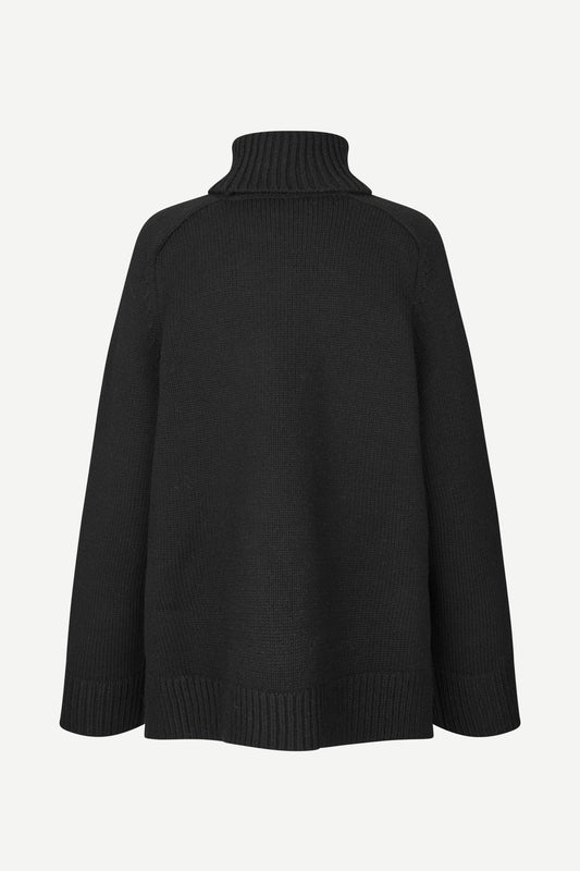 A black knit turtleneck sweater shown from the back, featuring a ribbed high collar, shoulders, cuffs, and hem, set against a plain light gray background.