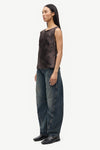 Woman wearing a patterned top and jeans on a white background