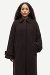 A woman wearing a dark brown wool-blend coat with a collar, front button closure, and large patch pockets, photographed against a light gray studio background.