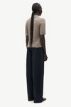 A model shown from the back wearing a beige short-sleeve knit top and dark navy wide-leg trousers, set against a plain light gray background.